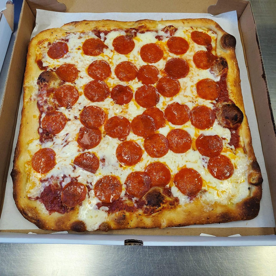 A rectangular pepperoni pizza with a thick crust sits in an open cardboard box.
