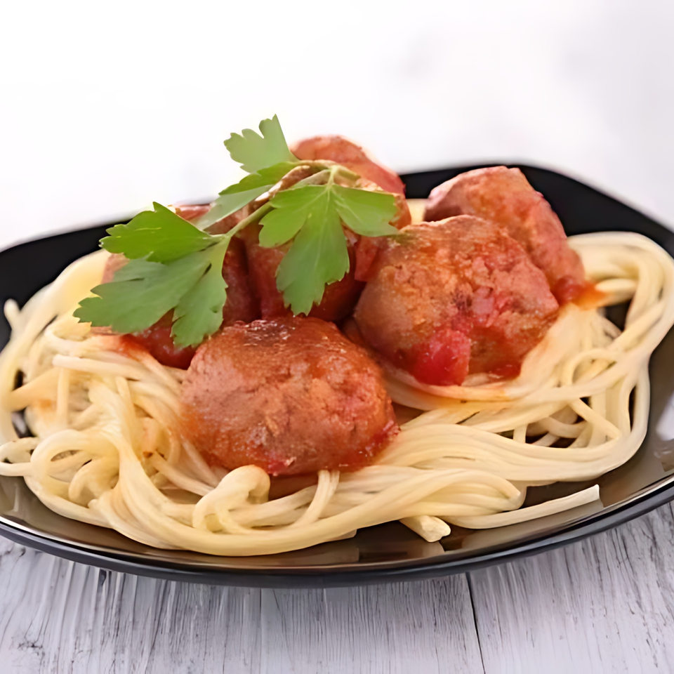 Spaghetti and meatballs with tomato sauce and parsley on a black plate.