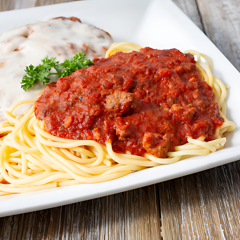 Spaghetti with meat sauce and a side of chicken parmesan on a white plate.